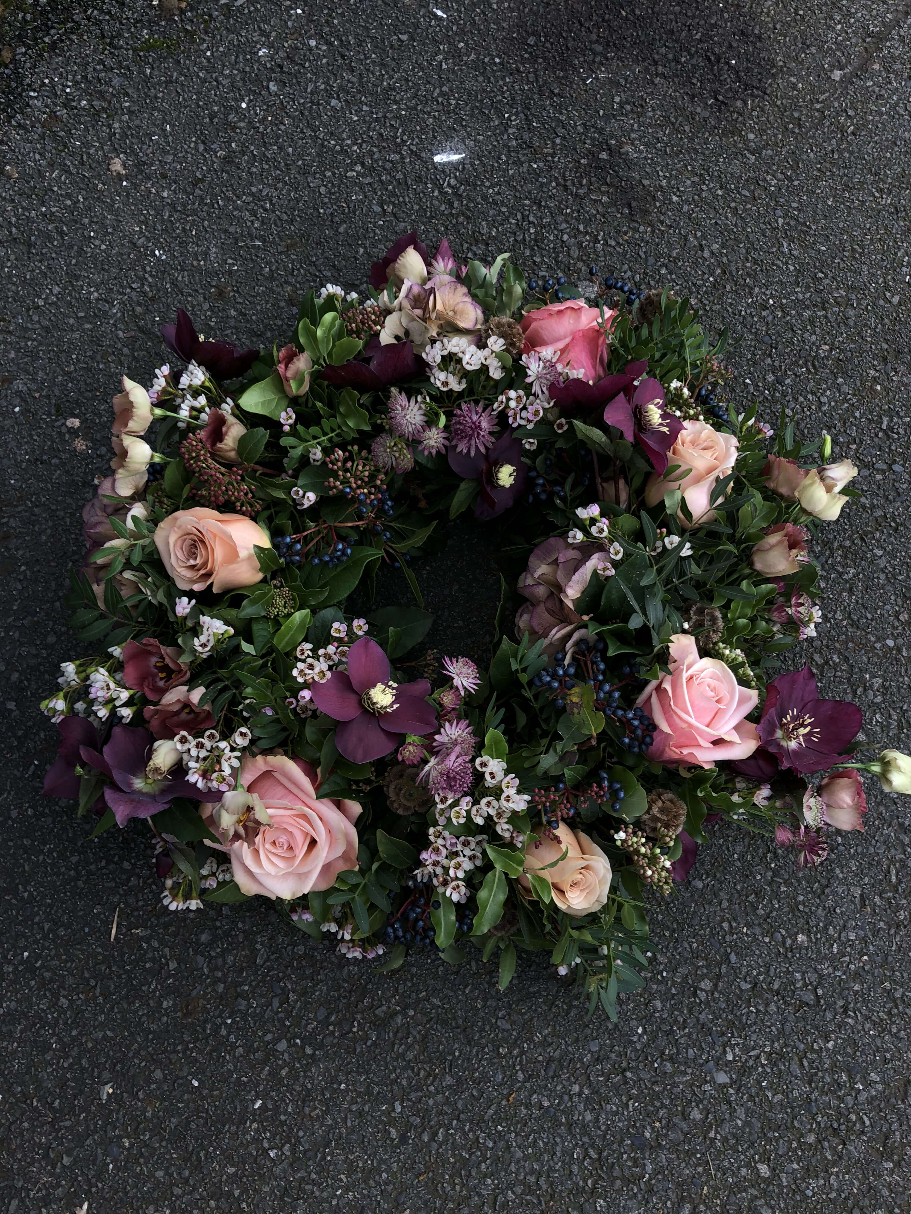 Funeral flower wreath with deep purple and soft pink flowers.