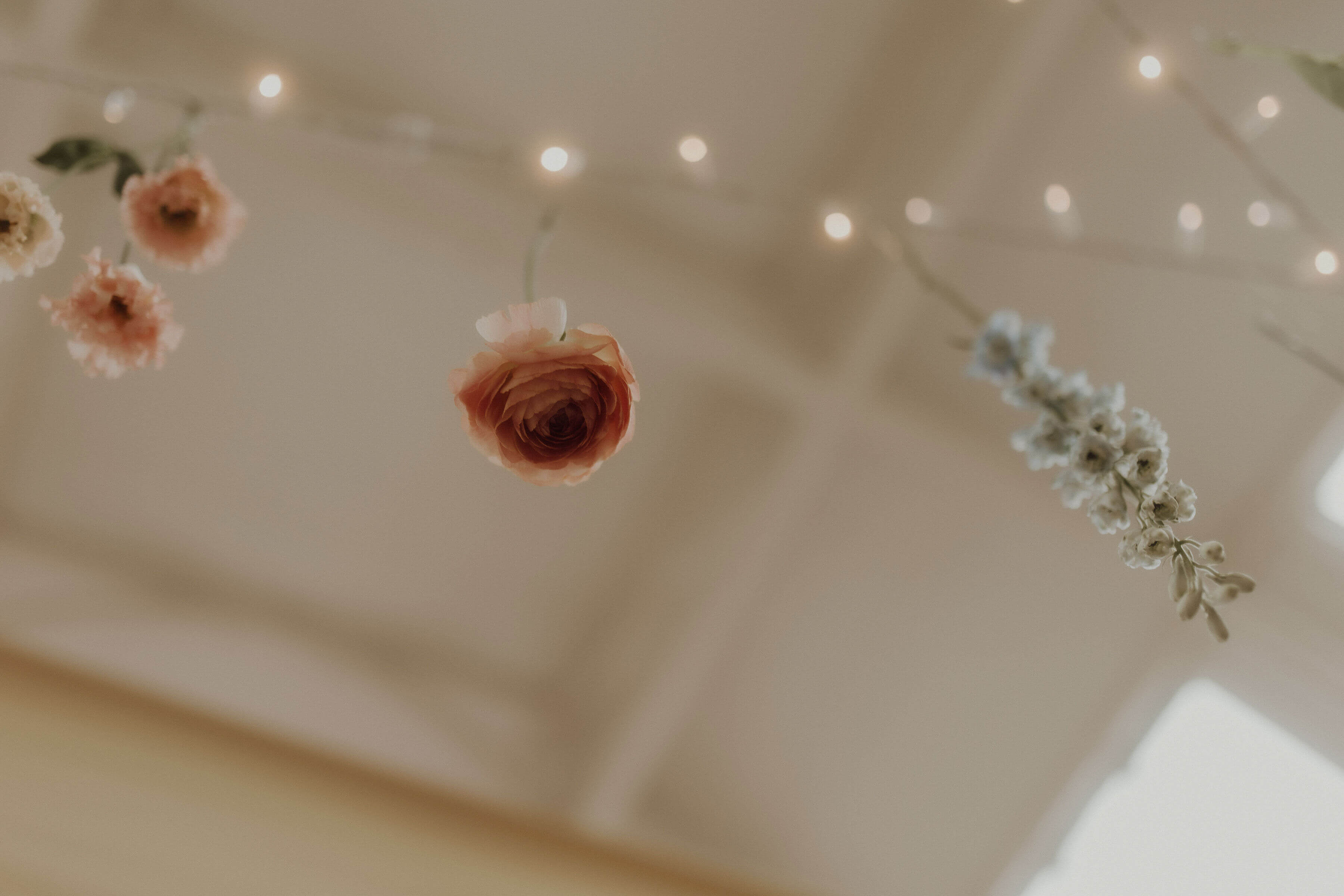 Elegant wedding flowers suspending from a ceiling with fairy lights.