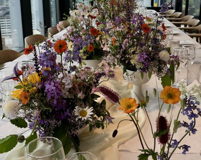 Decorative table setting with floral arrangements and wine glasses in a modern indoor setting.